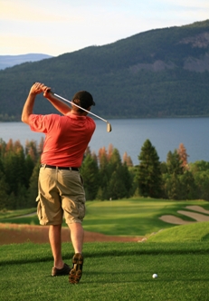 Man golfing on a scenic course overlooking a lake.