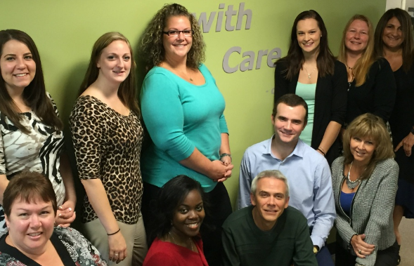 The Group Benefits Service Team smiling in front of a green wall.