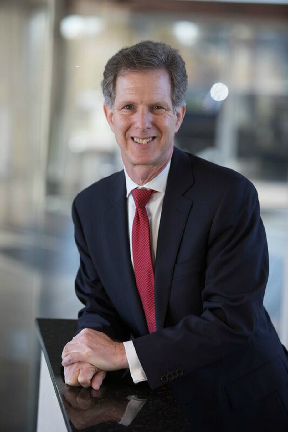 Smiling businessman in a suit and red tie at his desk