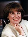 Smiling woman with brown hair and pearl necklace