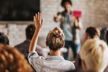Woman raising her hand at a frequently asked questions session