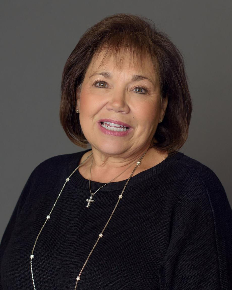 Smiling staff member with brown hair and cross necklace