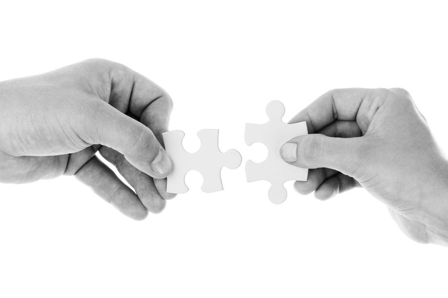 Two hands connecting puzzle pieces representing collaboration