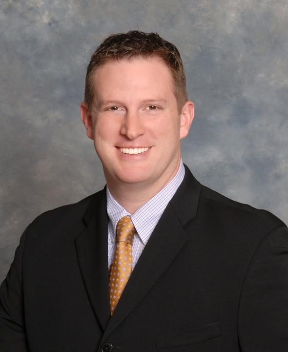 Smiling male associate in a suit and gold tie.