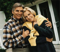 Happy retired couple smiling and embracing outdoors.