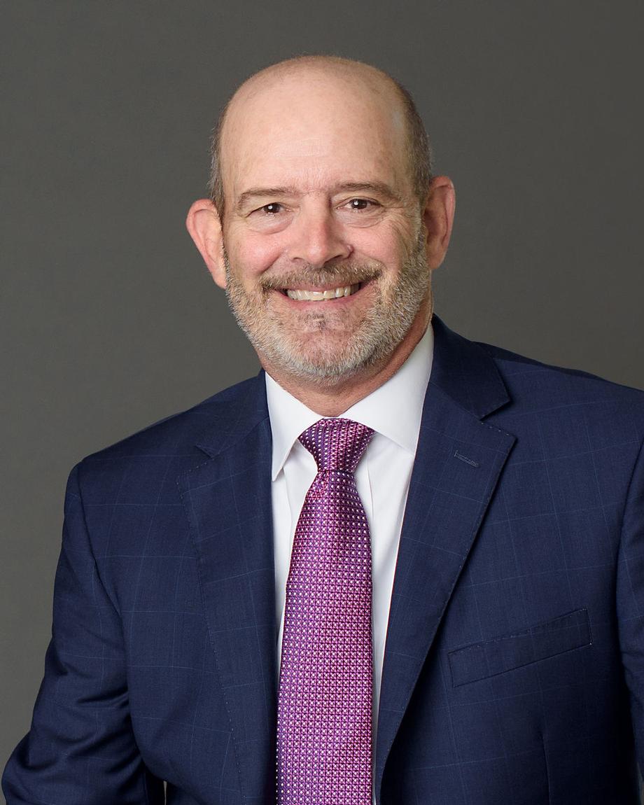 Smiling advisor in a blue suit and purple tie.