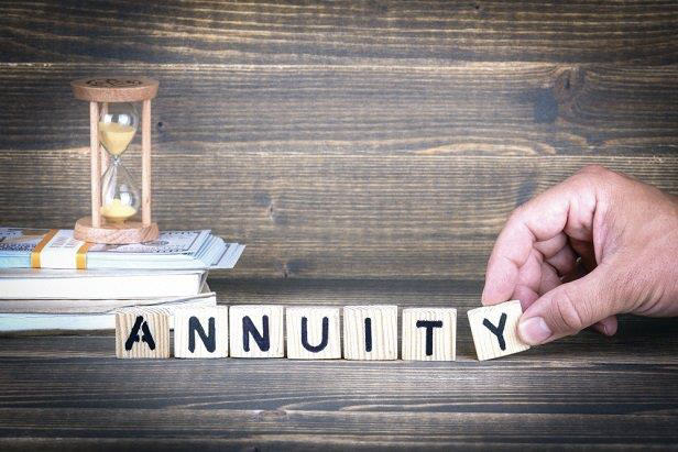Hand placing wooden blocks spelling ANNUITY near an hourglass