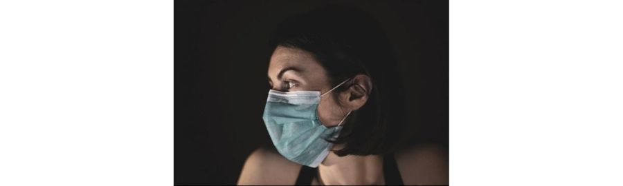 Woman wearing a medical face mask against a dark background