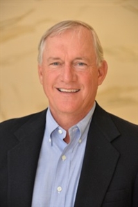 Smiling man in a dark suit and blue button-down shirt
