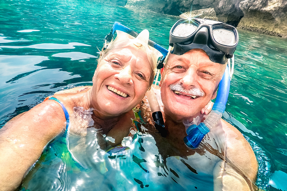 Smiling older couple snorkeling in clear blue water