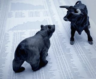 Bull and bear figurines facing each other on financial data