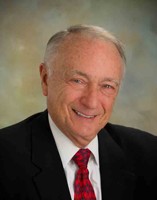 Smiling senior male team member in a suit and red tie