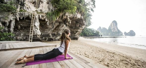 Woman in cobra yoga pose on a beach deck