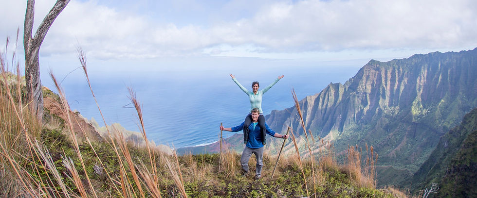Couple celebrating on a mountain ridge overlooking cliffs.