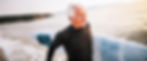 Smiling senior man in wetsuit with surfboard at beach