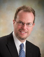 Smiling man with glasses and goatee in a suit and tie