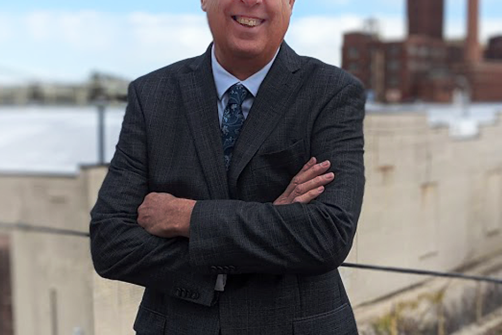 Smiling man in a suit with arms crossed outdoors