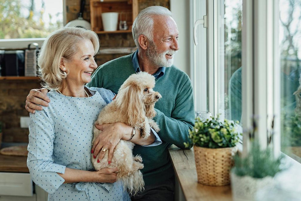 Senior couple with a small dog looking out a window.