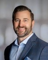 Smiling male associate in a suit jacket and collared shirt.