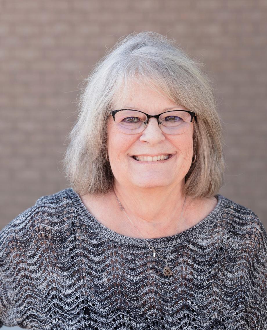 Smiling woman with grey hair and glasses on the team