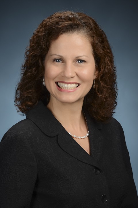 Smiling woman with curly hair in a black blazer