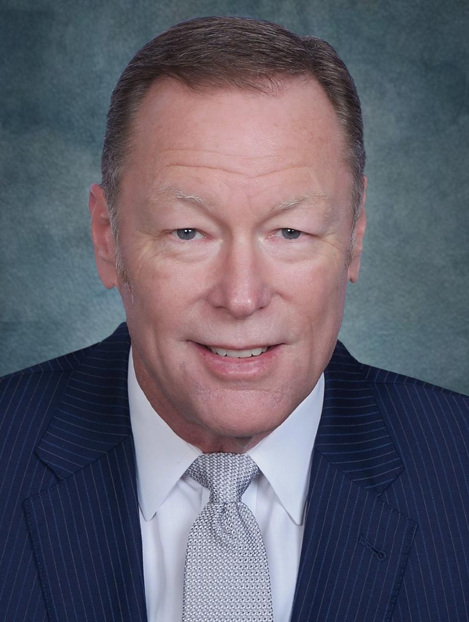 Professional headshot of a smiling male leader.