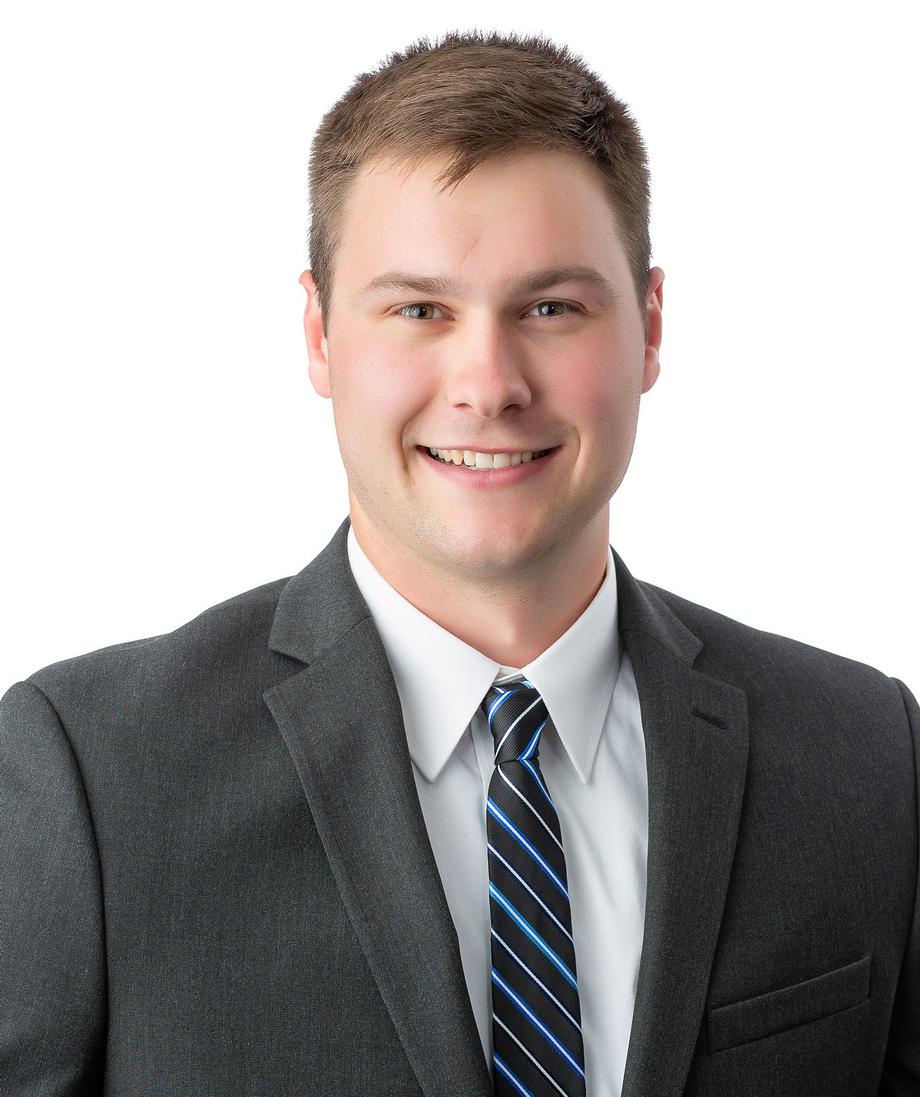 Smiling man in a grey suit and striped tie.
