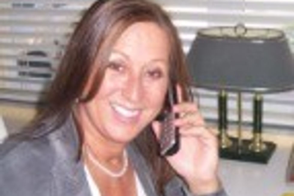 Smiling woman with brown hair talking on a cell phone.