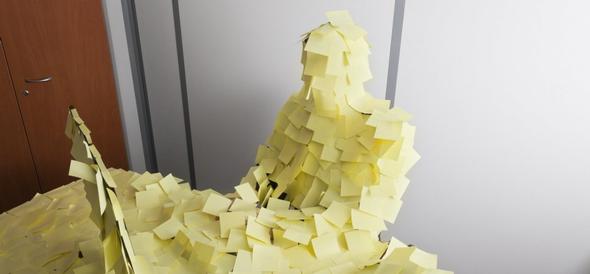 Human figure covered in yellow sticky notes at a desk