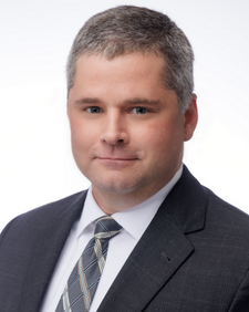 Professional headshot of a team member in a suit and tie.