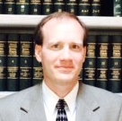 Associate in a suit in front of a law library bookshelf