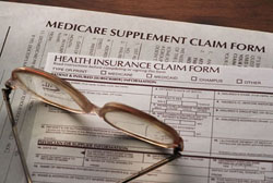 Medicare supplement and health insurance claim forms with glasses