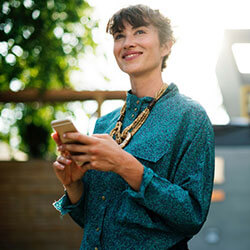 Smiling woman holding a smartphone outdoors