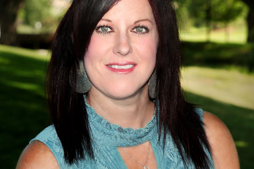 Smiling woman with dark hair in a teal top outdoors