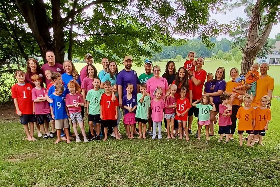 Large family group in colorful numbered shirts outdoors.