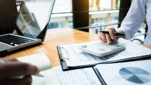 Accountant using calculator and documents on office desk