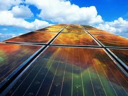 Solar panels reflecting a blue sky with clouds.