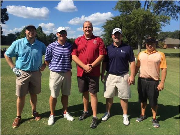 Five men in golf attire posing on a sunny golf course