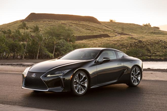 Dark luxury sports car parked against a scenic hill