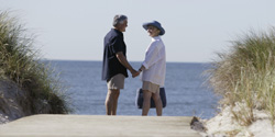 Senior couple holding hands on a beach path.