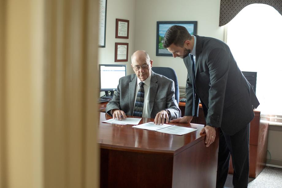 Two men in suits reviewing documents in a professional office.