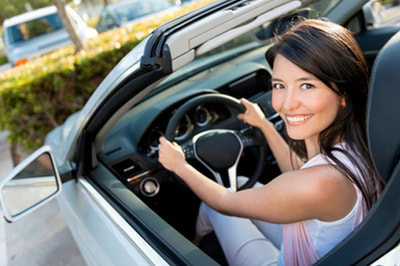 Smiling woman driving a car with personal auto insurance.