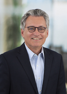 Smiling mature man with glasses in a dark blazer and blue shirt