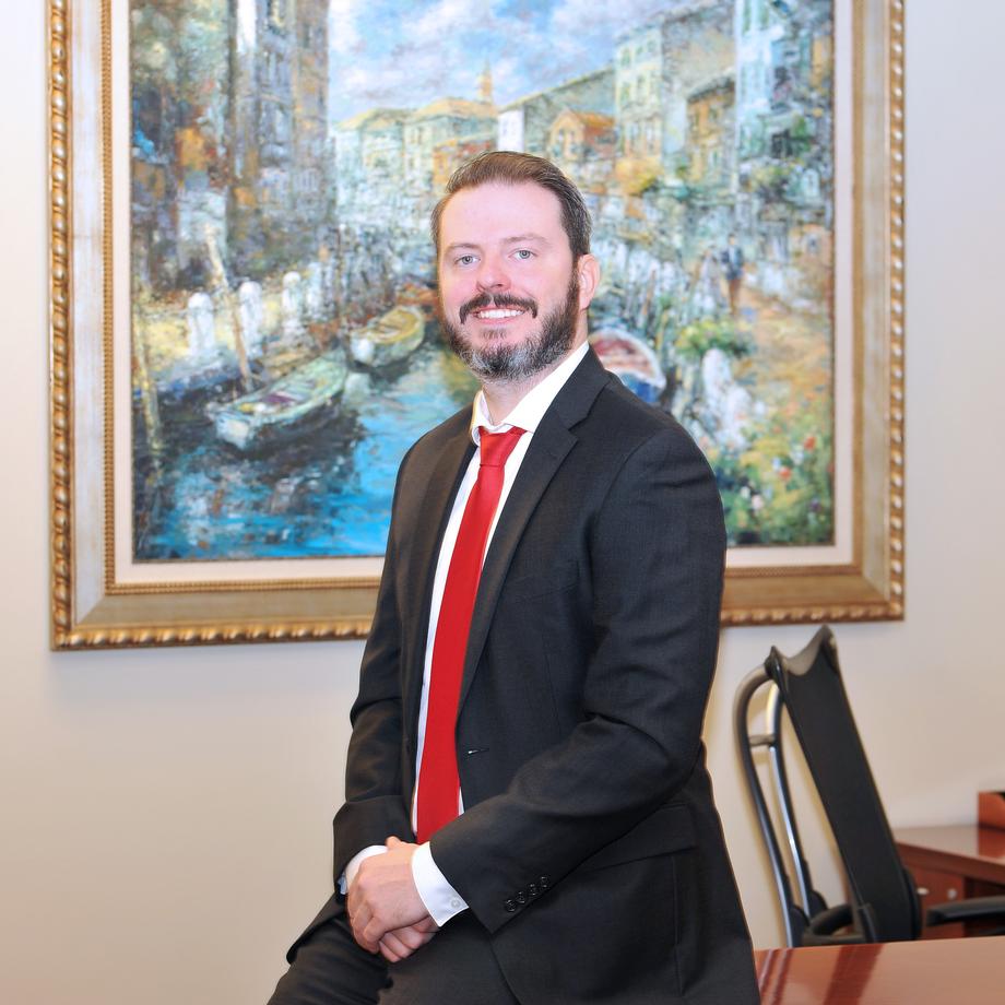 Smiling man in a black suit and red tie in an office