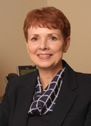 Smiling woman with short auburn hair in a navy blazer.