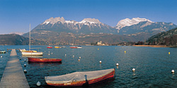 Boats on Lake Annecy with snow-capped mountains.