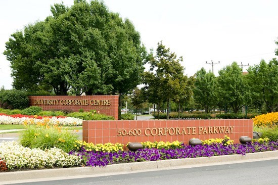 50600 Corporate Parkway sign with lush trees and flowers.