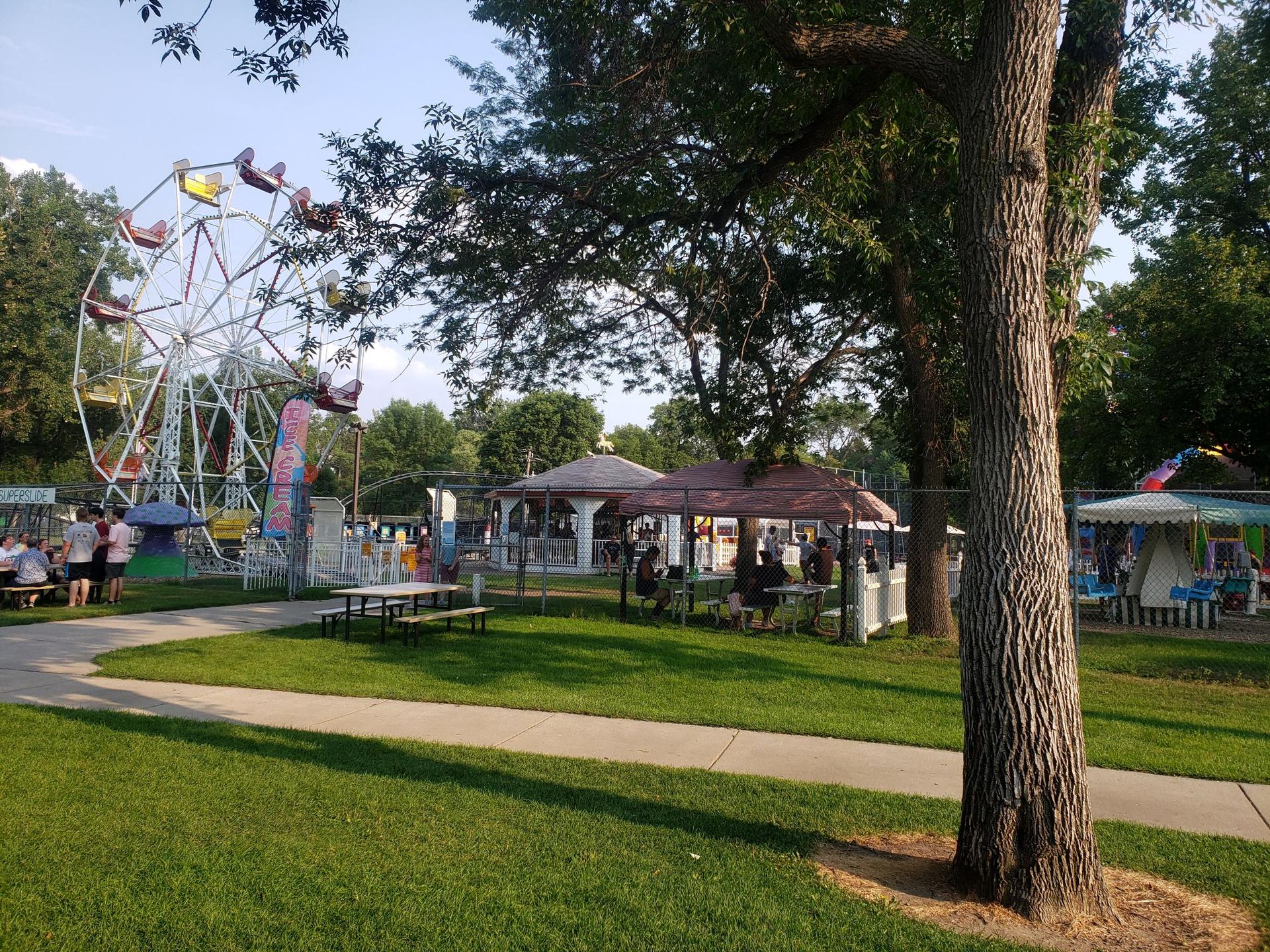 Ferris wheel and shaded picnic area at an outdoor fair