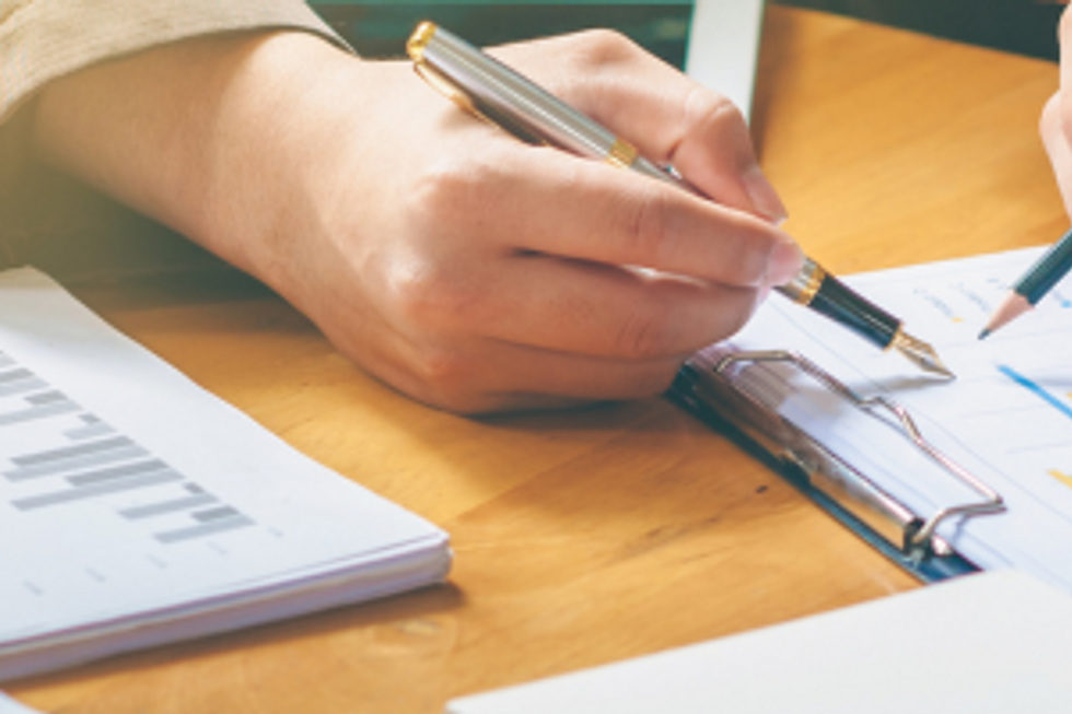 Hand holding a pen over business documents on a desk