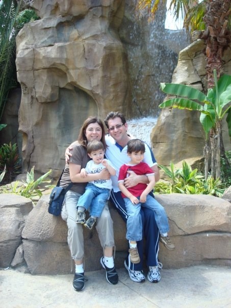 Aaron Herman and family posing by a rock waterfall.